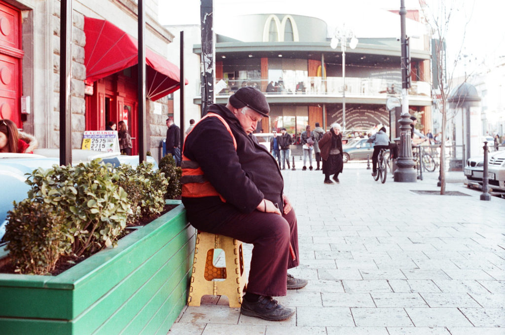 A man in the street sleeping on a chair
