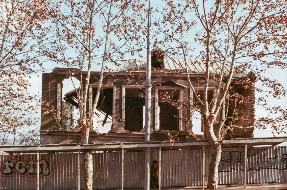 a woman passing in the street on the backdrop of an old crumbled building